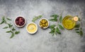 Composition with green and brown olives, extra virgin olive oil in glass bottle, olive tree branches on gray concrete