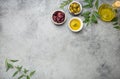 Composition with green and brown olives, extra virgin olive oil in glass bottle, olive tree branches on gray concrete