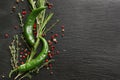 Composition with green chili, spices and fresh herbs on black textured background Royalty Free Stock Photo