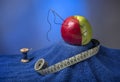 composition: green-red apple with the needle and thread on a blue towel. Near it blue coil of thread and centimeter for sewing Royalty Free Stock Photo