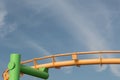 Composition with green and yellow painted carnival ride against a blue sky with wispy clouds, copy space