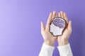 Composition of hands holding head silhouette with purple brain on purple background, with copy space