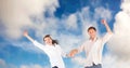 Composition of happy couple celebrating, holding hands jumping in the air smiling, over blue sky Royalty Free Stock Photo