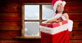 Composition of happy woman in santa hat carrying gifts in sack by window, copy space Royalty Free Stock Photo