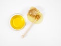 Composition of honey in a bowl, a wooden dipper for honey and a spreading drop of honey on a white table, bee honeycomb