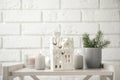 Composition with house shaped candle holder on white table near brick wall. Christmas decoration Royalty Free Stock Photo