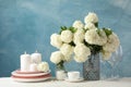 Composition hydrangea flowers and candles against blue background. Romantic evening