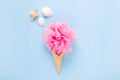 Composition of ice cream cone with pink wisp of bast on a light blue background