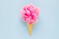 Composition of ice cream cone with pink wisp of bast on a light blue background