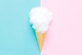 Composition of ice cream cone with pink wisp of bast on a light blue background