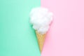 Composition of ice cream cone with pink wisp of bast on a light blue background