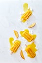 Composition of juicy pieces of peach, ice and melting ice cream on a stick with splashes on a gray marble table with Royalty Free Stock Photo