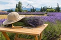 Composition of lavender bouquet, large sunscreen hat and a sickle on a wooden table