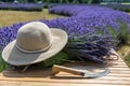 Composition of lavender bouquet, large sunscreen hat and a sickle on a wooden table