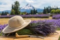 Composition of lavender bouquet, large sunscreen hat and a sickle on a wooden table