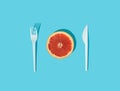 Composition made with citrus sliced with fork and knife on sunny blue background. Creative heathy snack, food, fruit or