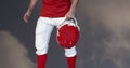 Composition of male american football player holding helmet over blue sky with clouds Royalty Free Stock Photo