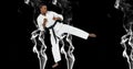 Composition of male martial karate artist with black belt kicking over smoke and copy space Royalty Free Stock Photo