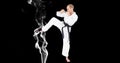 Composition of male martial karate artist with black belt kicking over smoke and copy space Royalty Free Stock Photo