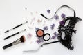 A masquerade black mask, spring flowers and cosmetics on a white background. Royalty Free Stock Photo