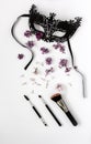 A masquerade black mask, spring flowers and tassels on a white background.