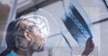 Composition of medical data processing with human brain over female doctor checking x ray Royalty Free Stock Photo