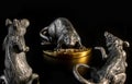 Composition from metal figures: rats are fighting for a piece of cheese. Products from silver and gold. The concept of the zodiac