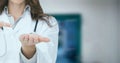 Composition of midsection of female doctor in lab coat pointing over out of focus hospital