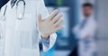 Composition of midsection of male doctor in lab coat hand in surgical glove on out of focus hospital Royalty Free Stock Photo