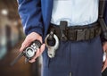 Composition of midsection of male security guard holding walkie talkie over blurred background