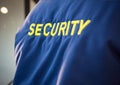 Composition of midsection of security guard blue jacket with yellow text over blurred background