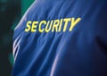 Composition of midsection of security guard blue jacket with yellow text over green background