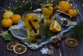 Composition of mugs with fragrant tea with slices of lemon, orange and cinnamon on a metal tray, next to decorative snowflakes, Royalty Free Stock Photo