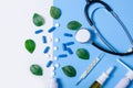 Composition nasal spray, throat spray, stethoscope, white jar with pills, thermometer nature green leaf Royalty Free Stock Photo
