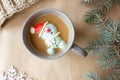 Composition of the new year  a gray mug with coffee marshmallows in the form of a snowman in a red hat Royalty Free Stock Photo
