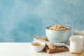 Composition oatmeal flakes and milk on white table. Cooking breakfast