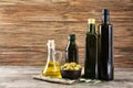 Composition with olive oil in bottles and jug on wooden background Royalty Free Stock Photo