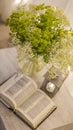 Composition: an open Bible, a bouquet of wildflowers in a vase and a decorative flashlight with a candle on the nightstand against
