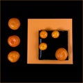 Composition of orange mandarin and black square plate on an orange table Royalty Free Stock Photo
