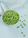 Composition with organic frozen vegetables on a light blue background. Green peas in a bowl. Royalty Free Stock Photo