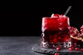 A composition of a organic pomegranate drink and cut garnet on a black background. Healthful and fresh red cocktails. Royalty Free Stock Photo