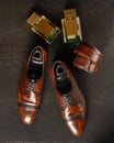 Composition of a pair of men`s shoes of brown color, two bottles of men`s perfume and men`s trouser belt against the background