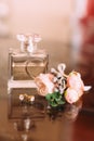 The composition of the parfum, golden earrings and lovely boutonniere of pink roses.