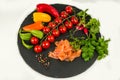 Composition of pasta fresh tomato, pepper, fish, radish on black stone board, white background. Royalty Free Stock Photo