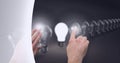 Composition of person touching lit light bulb with row of light bulbs on grey background Royalty Free Stock Photo