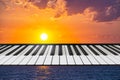 Composition of piano keyboard on marine background with a setting sun.