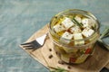 Composition with pickled feta cheese in jar on blue wooden table Royalty Free Stock Photo