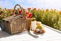 Composition with picnic basket and bottle of wine on wooden table in lily field. Space for text Royalty Free Stock Photo