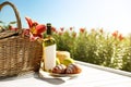 Composition with picnic basket and bottle of wine on wooden table in lily field. Space for text Royalty Free Stock Photo