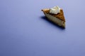 Composition of piece of pumpkin pie with whipped cream on blue background